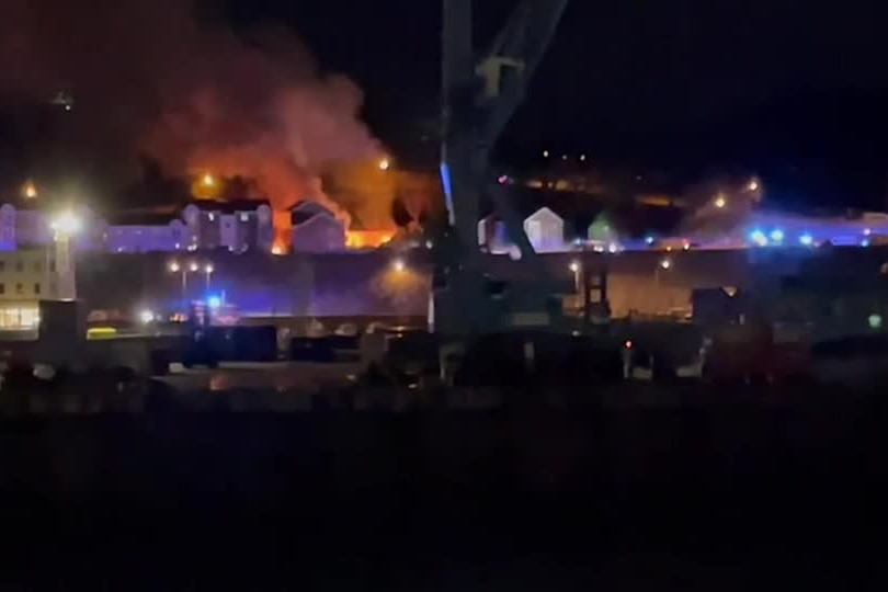 Fire and smoke seen rising from an apartment building at night.