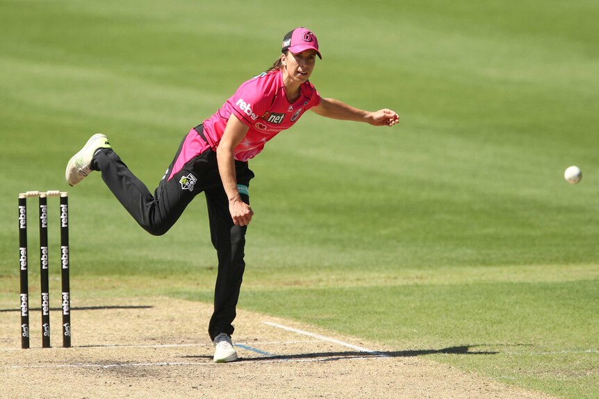 A cap-wearing bowler delivers a ball during a Women's Big Bash League game.