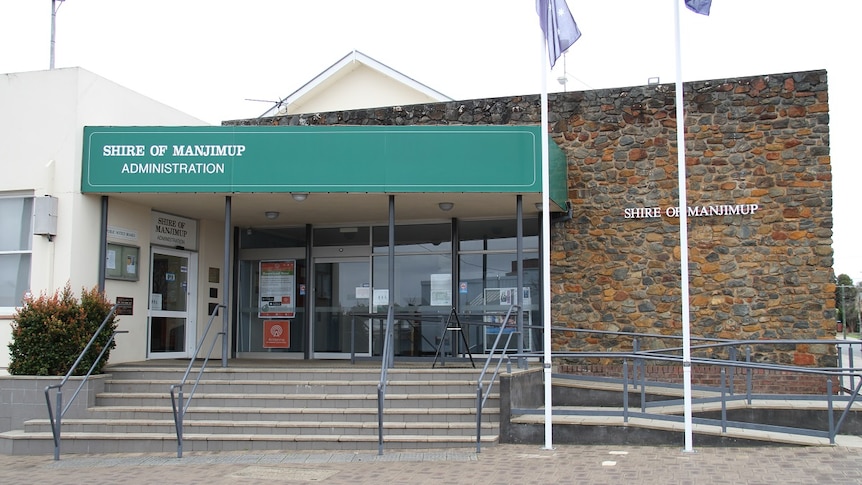 The exterior of an administrative building with two flag poles in front of the building  