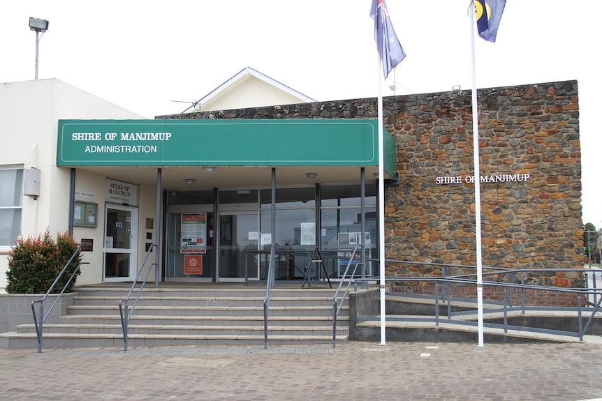 The exterior of an administrative building with two flag poles in front of the building  