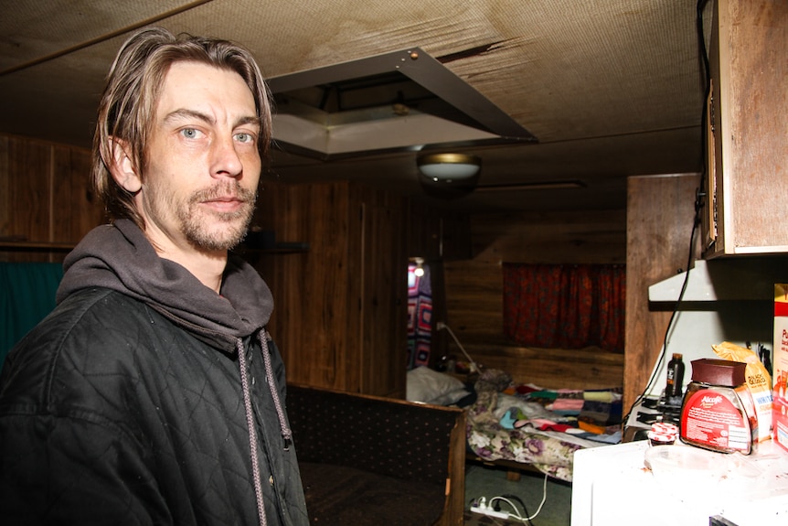 Luke Skinner inside his small  caravan with the bed in the background.