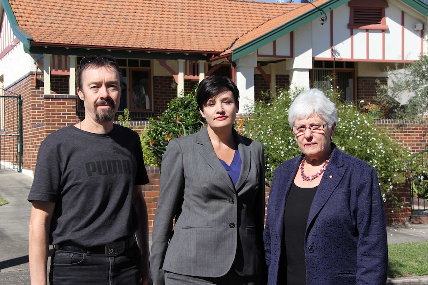 Three people standing in front of the house.