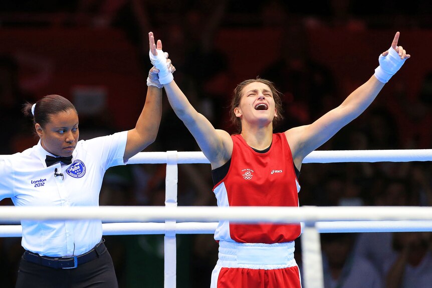 Katie Taylor raises both her arms and holds her head back with her mouth open