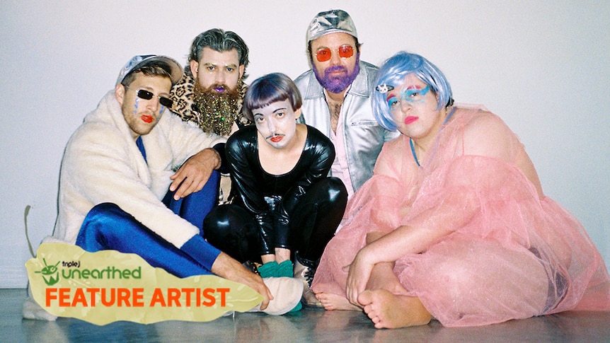 Five of the band member's of Alter Boy sit wearing costumes in front of a white wall with the Unearthed Feature Artist logo.