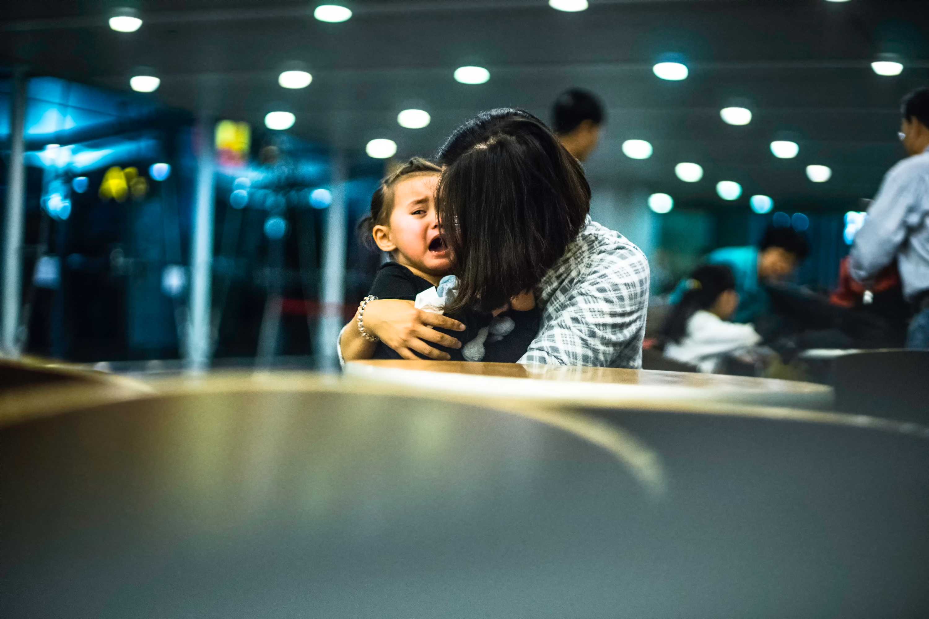  Une petite fille est réconfortée par sa mère alors qu'elle pleure dans un espace public d'un aéroport.