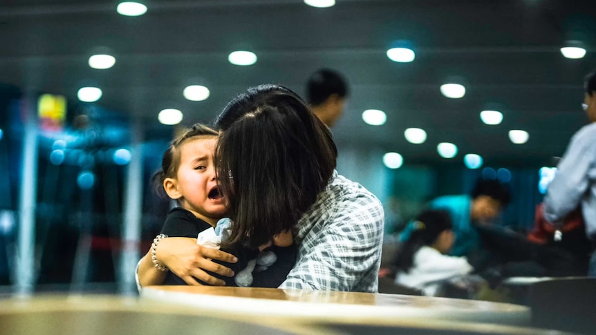 A little girl is comforted as she cries.