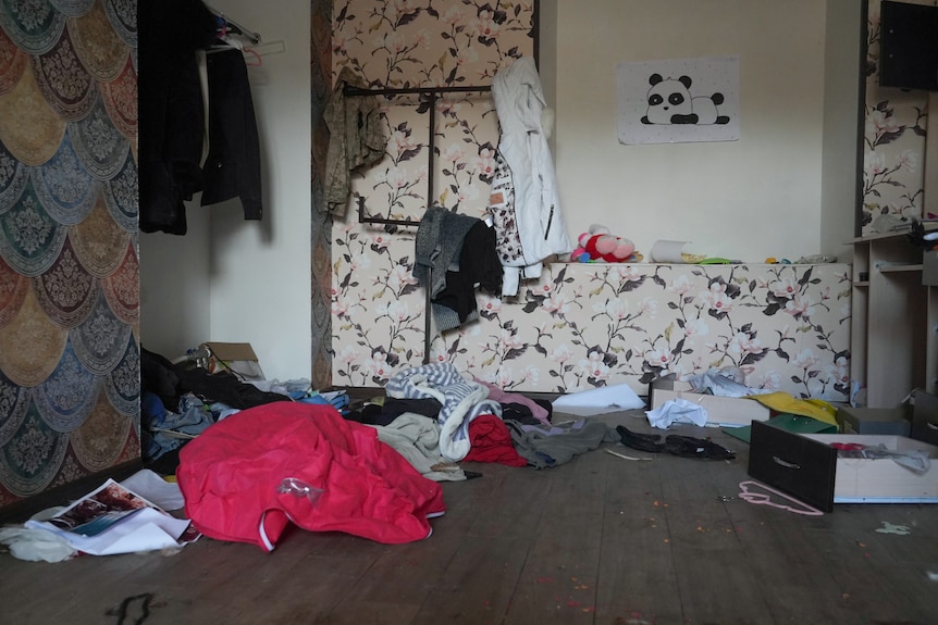 A room with clothes pulled out of the closet and strewn on the floor