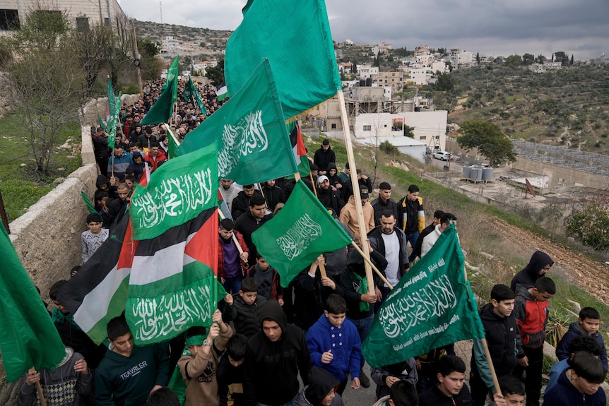 A group of people carrying hamas and palestinian flags. 