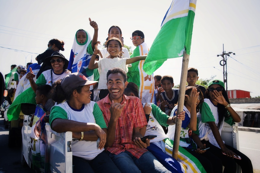 Young men and women campaigning in the Timor-Leste elections hold green, white and blue flags