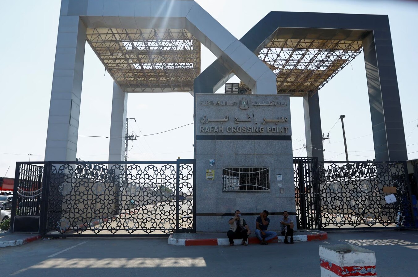 People sitting in front of a large iron gate 