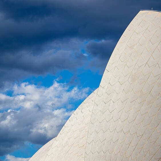A close up of the sails of the Sydney Opera House with blue skies and light clouds in the background