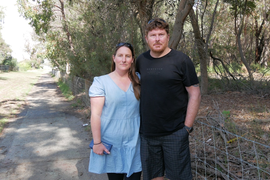 A woman and man standing to the right of a footpath.
