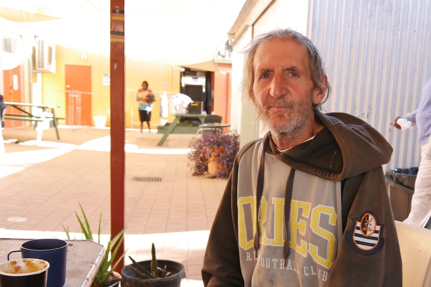 David Pearsall sits on a chair in the courtyard of a community centre in Alice Springs.