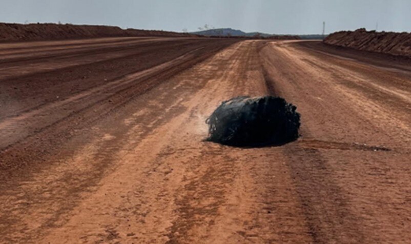 a black object on a dusty red dirt road 