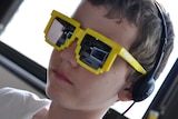 A boy wearing 8-bit sunglasses playing a special version of video game Minecraft