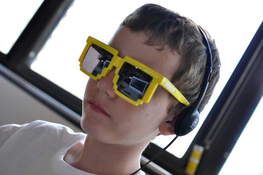 A boy wearing 8-bit sunglasses playing a special version of video game Minecraft