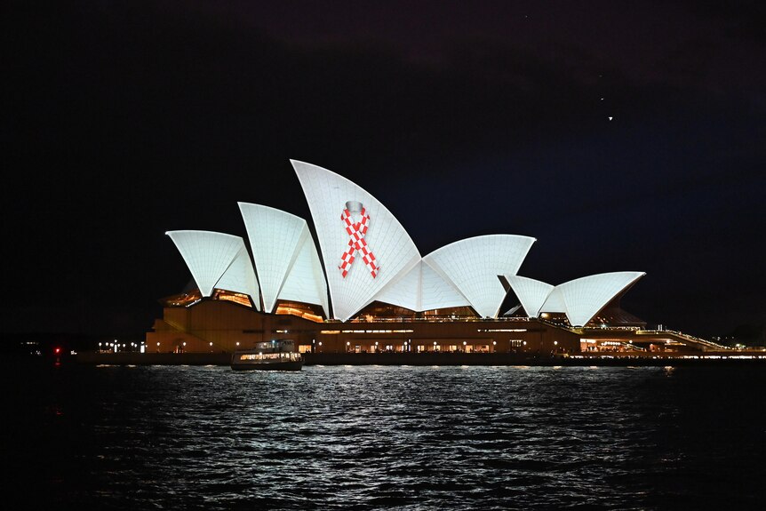 the sails of the opera house illuminated with a red and white ribbon