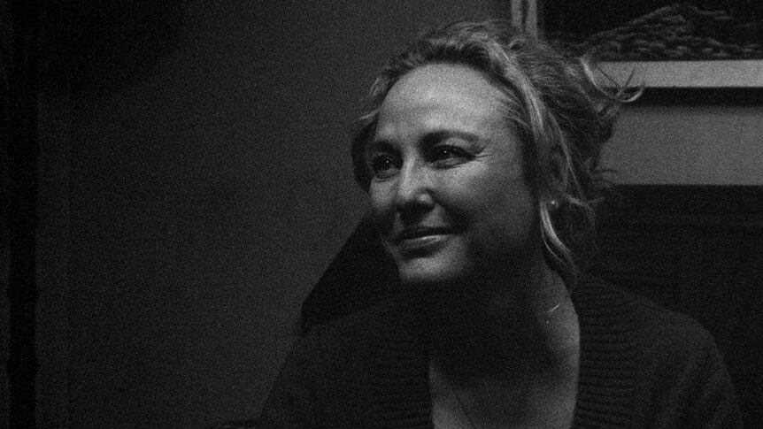 Black and white close-up still of Virginia Madsen smiling in 2018 film 1985.