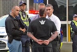 Unidentified Comanchero speaks to police at bikie raid at South Melbourne