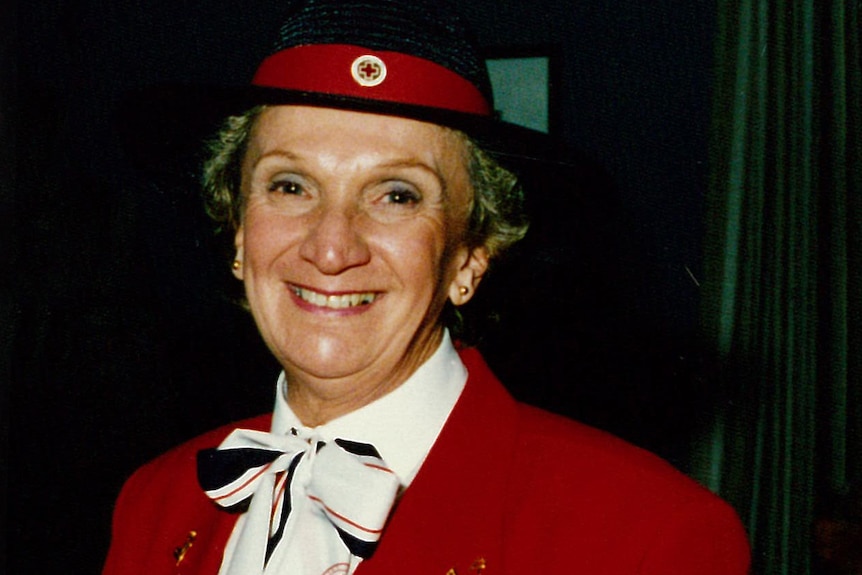 A photo of a middle-aged Yvonne Kennedy, with short fair hair and wide smile, dressed in Red Cross uniform. 