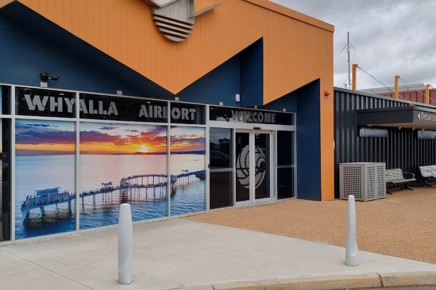 An orange and blue building with signs reading Whyalla airport