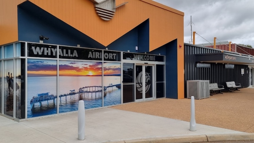 A strikingly-coloured building with a sign that reads "Whyalla Airport".