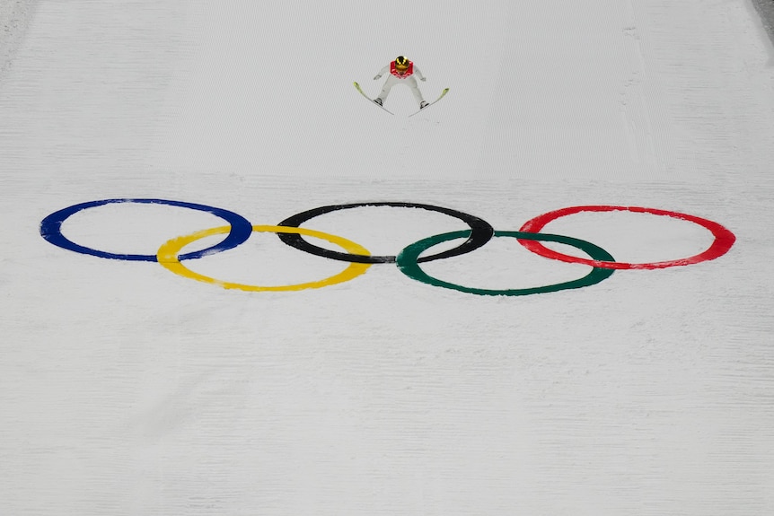 Killian Peier, of Switzerland, soars through the air over the Olympics symbol in the ski jumping in Zhangjiakou