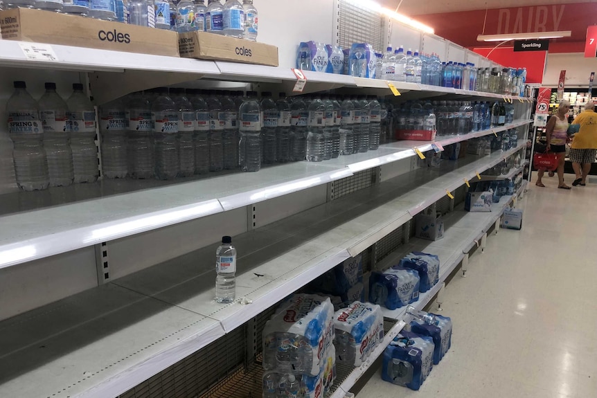 A Coles shelf only half stocked with water.