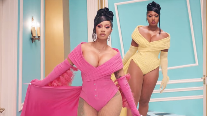 Cardi B and Megan Thee Stallion look at the camera wearing colourful outfits