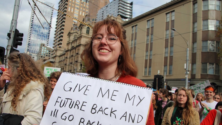A student holding a sign that says give me back my future and I'll go back to school.