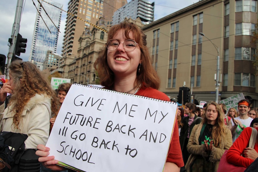 A student holding a sign that says give me back my future and I'll go back to school.