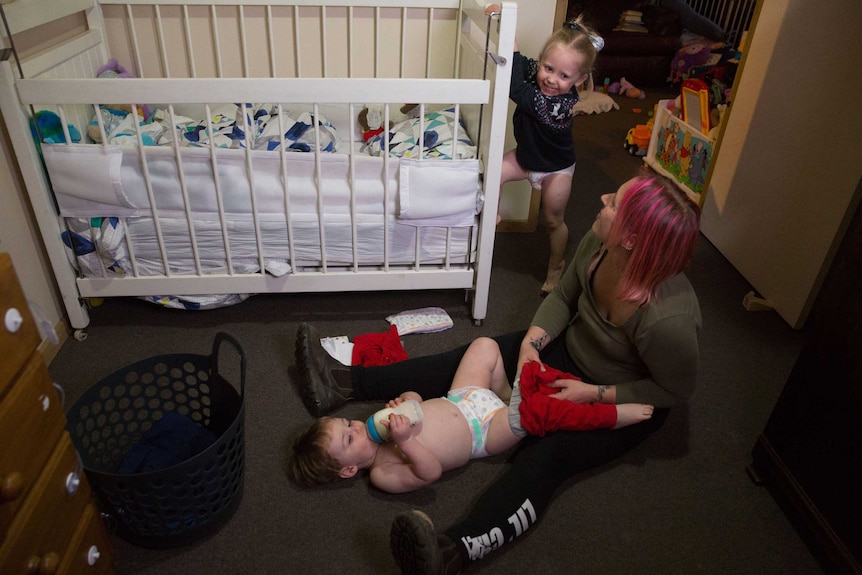 Amber changes Roman on the floor while Nara plays in the background