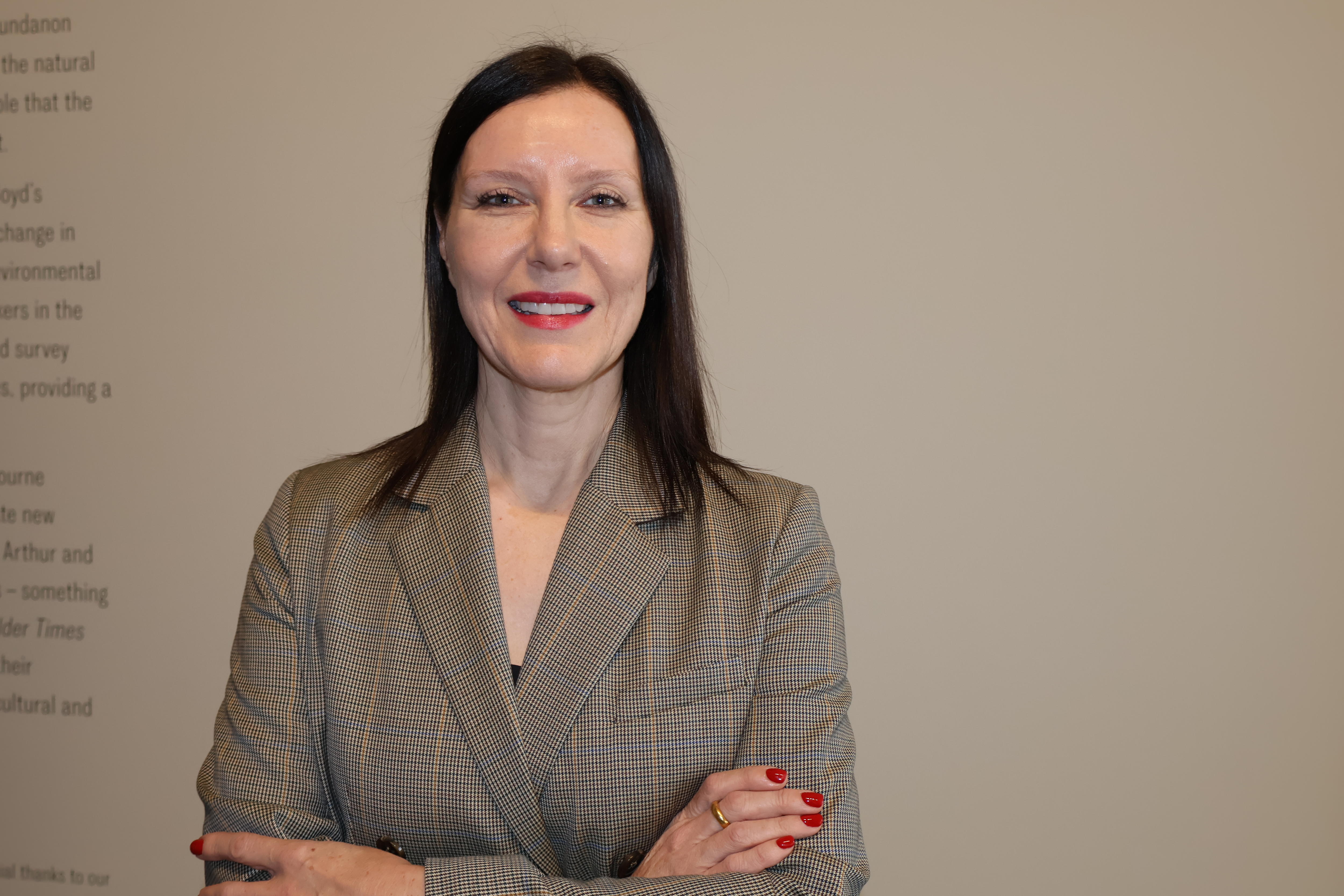 Woman smiles in front of a while wall