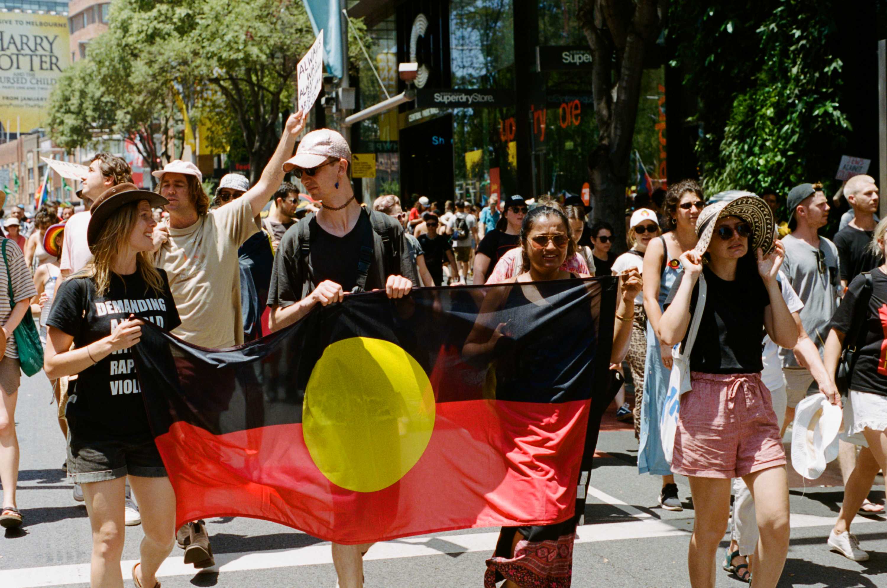 A group of marchers holds a large banner of the Aboriginal flag during the Yabun Festival, Sydney in 2019.