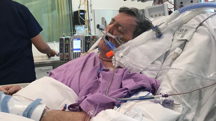 A man in a hospital bed with breathing tubes in his nose.
