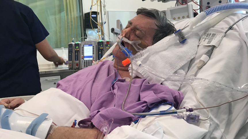 A man in a hospital bed with breathing tubes in his nose.