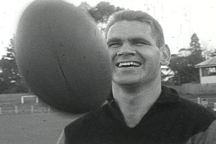 A young football player runs on the field in a striped guernsey.