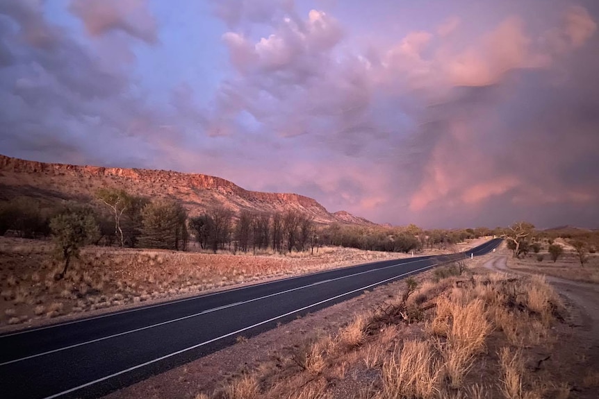 Storm clouds are seen at sunset over a road in Central Australia.