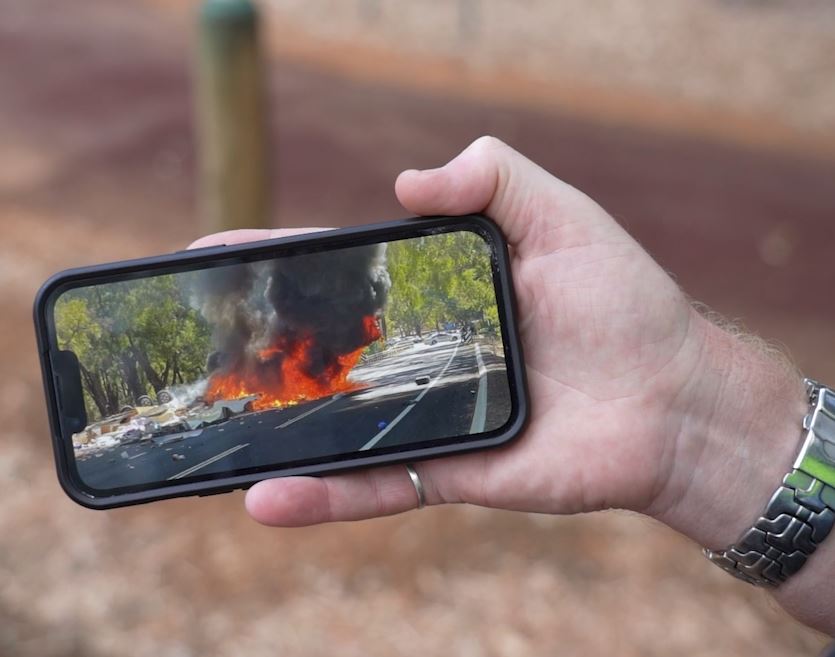 Car in flames captured on mobile phone screen. 