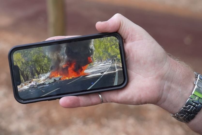 Car in flames captured on mobile phone screen. 