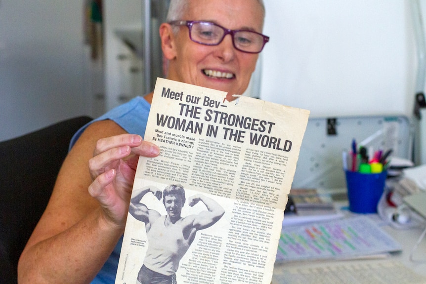 Bev Francis holds up a newspaper clipping which says Strongest Woman in the World
