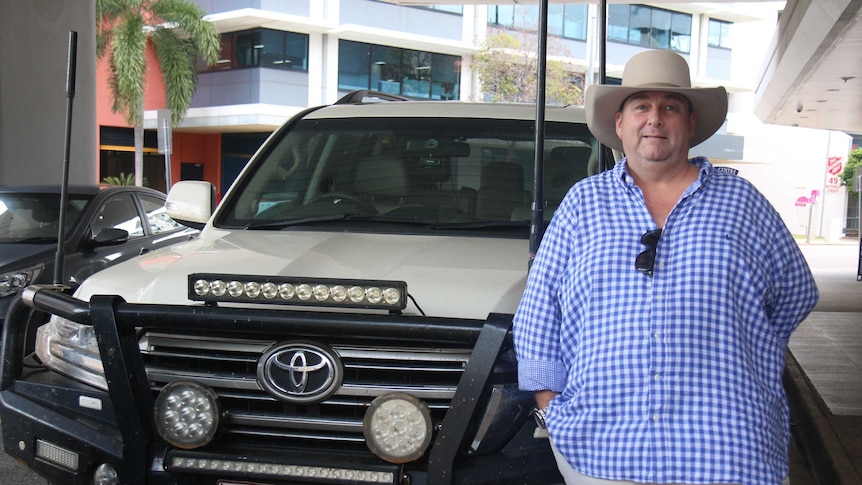 A man stands by a four-wheel drive.