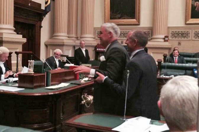 Michael Atkinson is led to the Speaker's chair