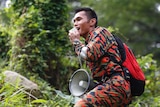 A member of a rescue team uses a loudspeaker as he conducts a search and rescue operation.