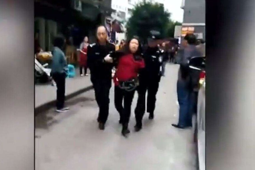A woman wearing a red jumper is arrested.