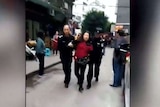 A woman wearing a red jumper is arrested.