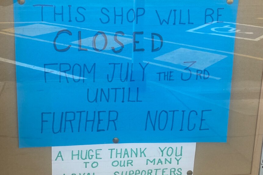A cardboard sign on an op shop door informing customers that the business has closed.