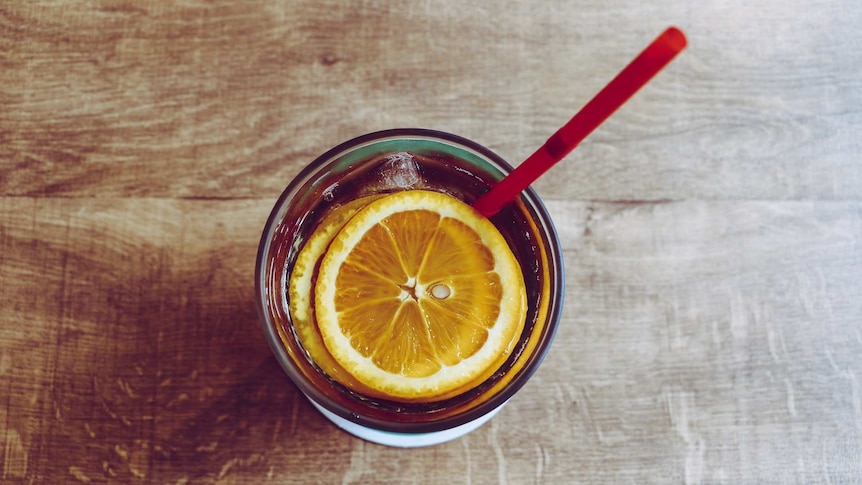 top view of a drink in a glass, with slices of orange and a straw