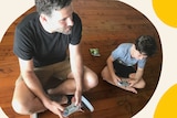 A man and a boy sit on the floor with computer game controllers