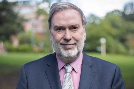 a man with a beard standing outdoors and looking at the camera